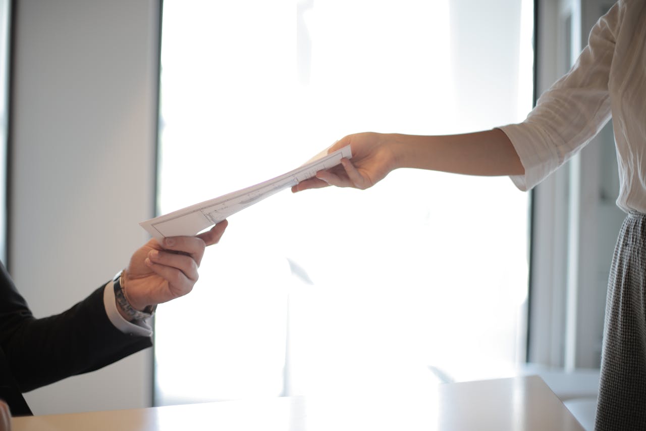 get-in-touch Close-up of hands exchanging documents in a business setting indoors.