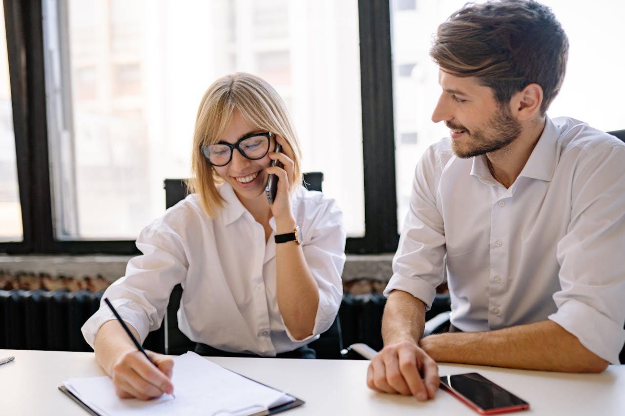 Two colleagues collaborate in a bright office, sharing ideas and notes.