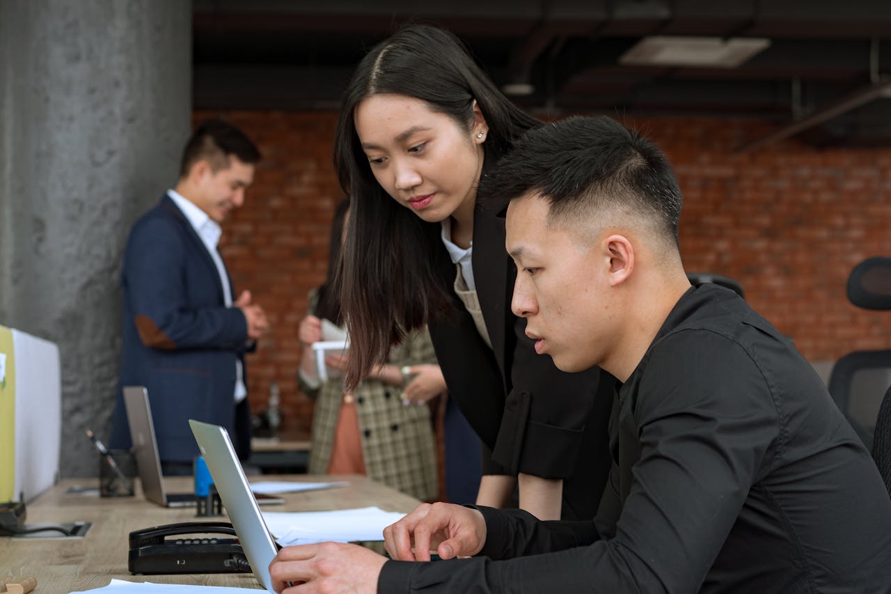 services-bg Professionals working together in a modern office setting around a laptop.